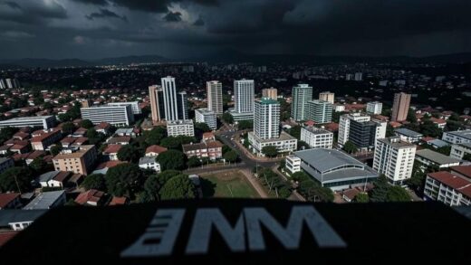 A dramatic aerial view of Kigali, Rwanda's capital, with modern buildings juxtaposed against a darkening sky. In the foreground, an IMF logo appears as a shadow. The image conveys economic uncertainty and crisis atmosphere.