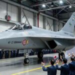 A majestic KF-21 Boramae fighter jet during its rollout ceremony at KAI factory in 2026, with Korean flags and officials celebrating, highlighting its sleek stealth design and national pride.