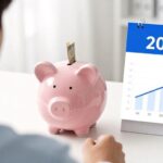 A modern savings account concept with a young person depositing money while receiving government support, digital interface showing growth charts, bright and hopeful atmosphere, 2026 calendar highlight