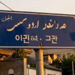 A symbolic street sign in Tehran showing 'Seoul Road' in both Persian and Korean scripts, with traditional Iranian architecture in the background, golden hour lighting, photorealistic style